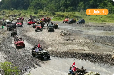 Off-road jeeps driving through a rocky riverbed in a scenic landscape near Jogja