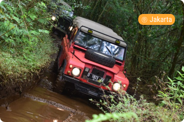 Jeep off-road driving through a muddy forest trail in Bogor